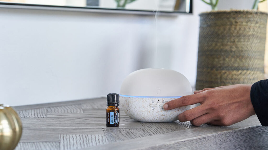 Флакон эфирного масла рядом с диффузором dōTERRA на столе