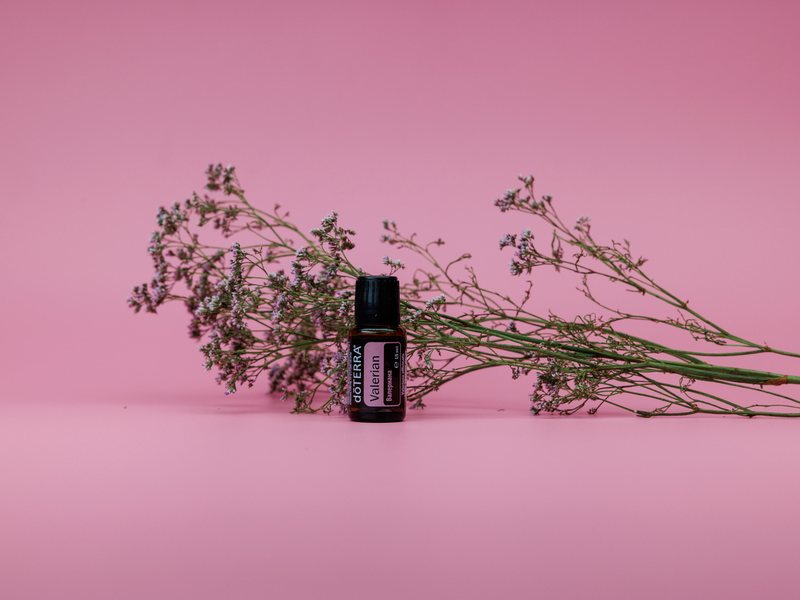 Эфирное масло валерианы dōTERRA на розовом фоне