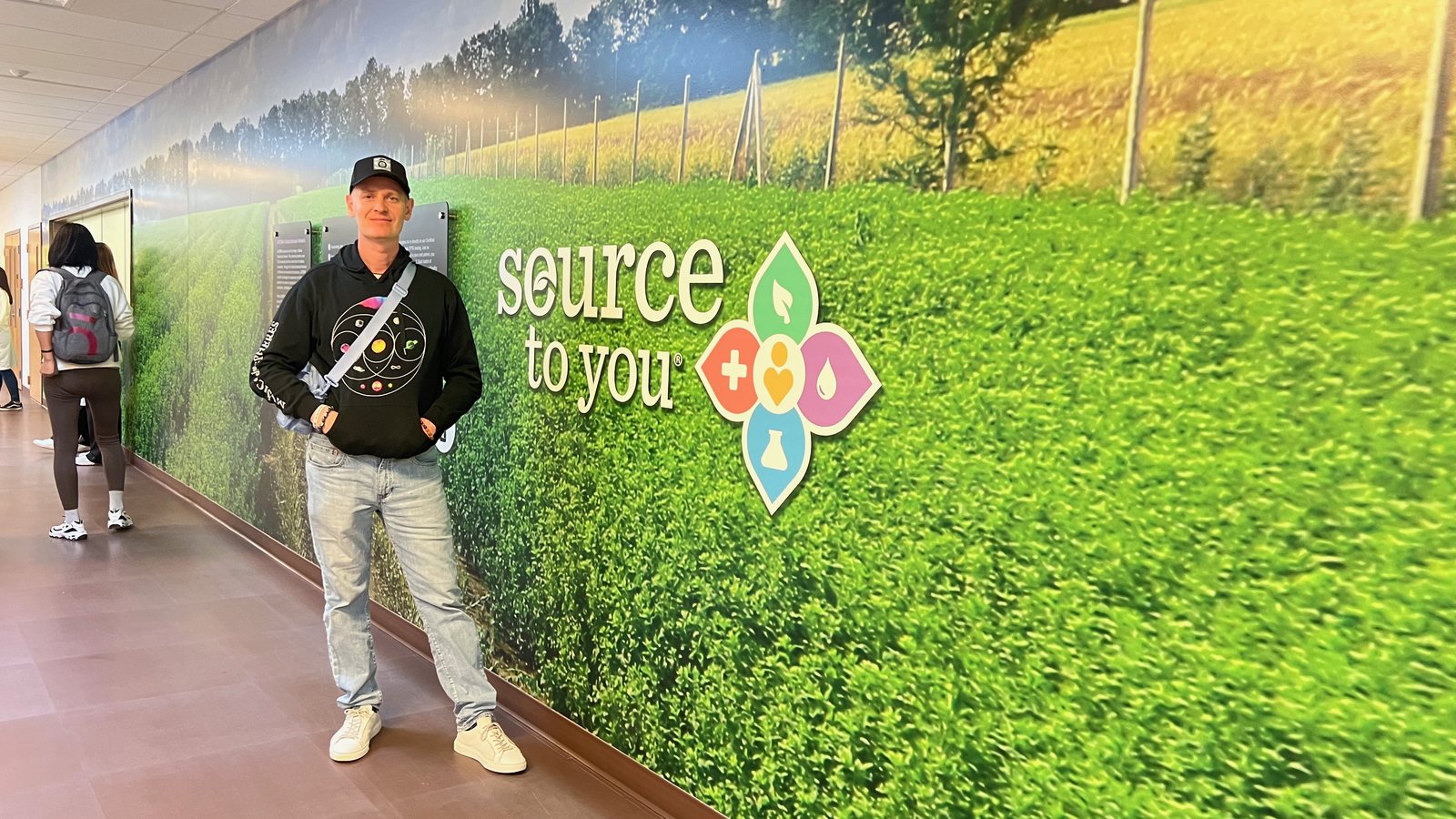 Алексей Валяев у стены Source to You в кампусе dōTERRA